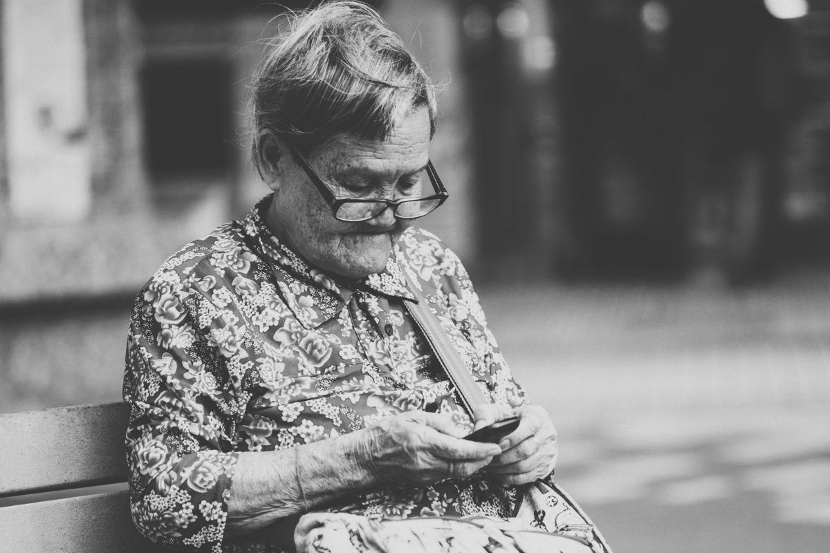 An elderly woman reading a message on her phone